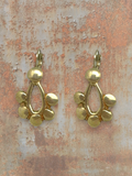 WILDSIDE gold metal geometric drop earrings with open teardrop and charm details. Lever-back closure.