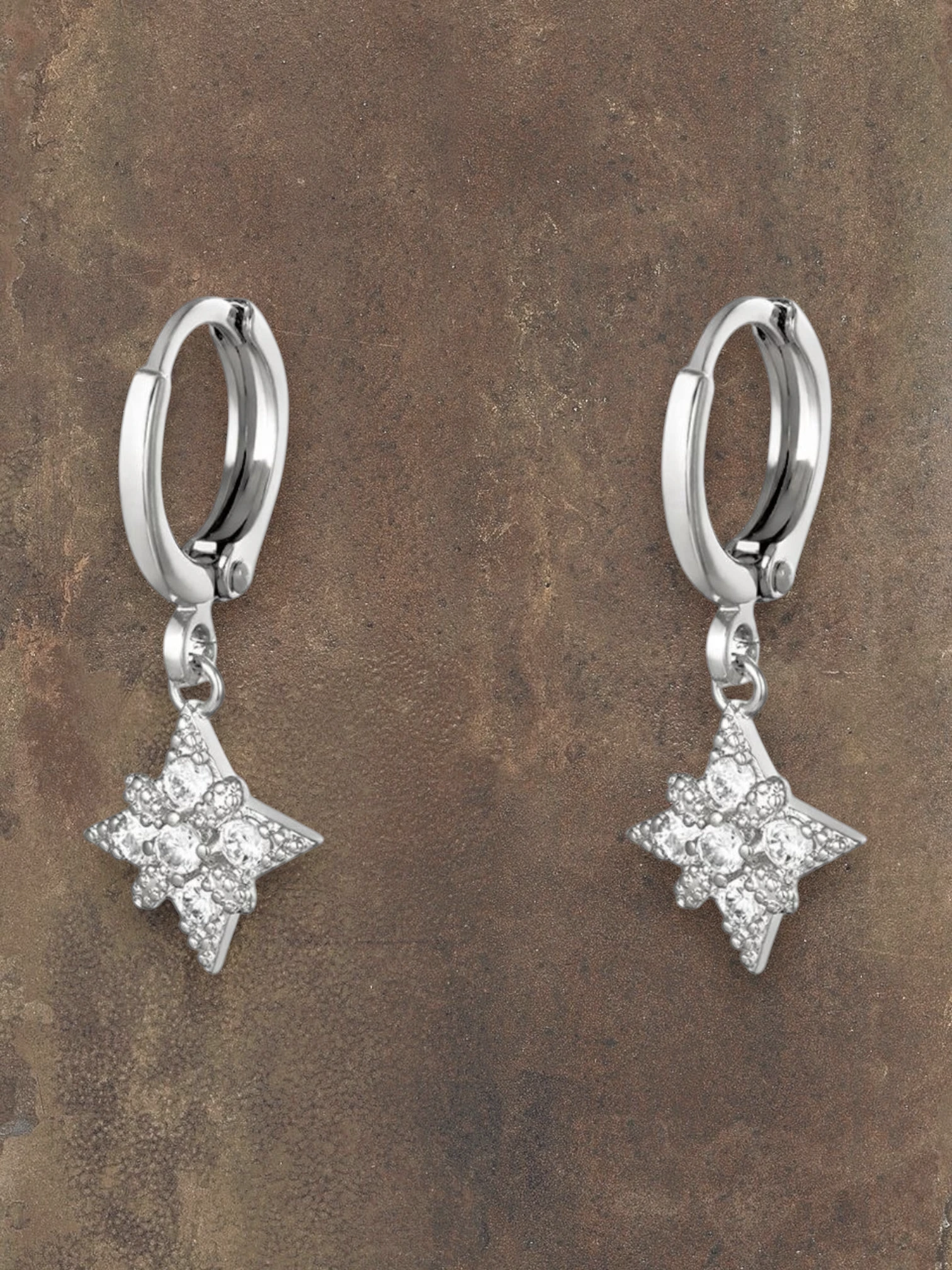 WILDSIDE silver steel hoop earrings with starburst charms encrusted with cubic zirconia stones.