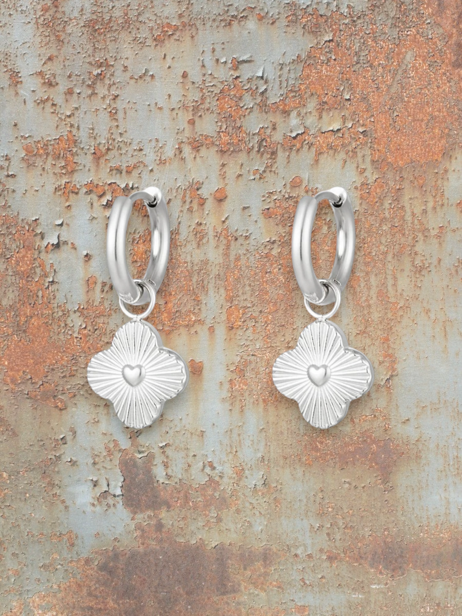 WILDSIDE silver stainless steel clover heart hoop earrings with radiating detail.