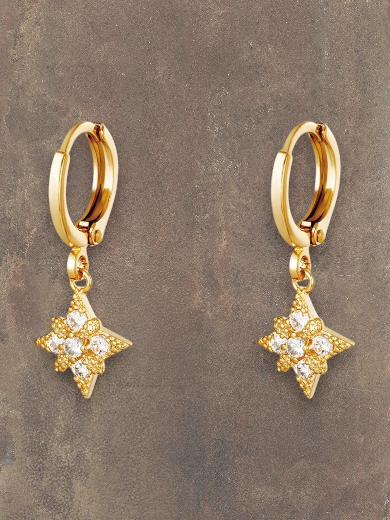 WILDSIDE gold hoop earrings with star-shaped pendants adorned with clear crystals.