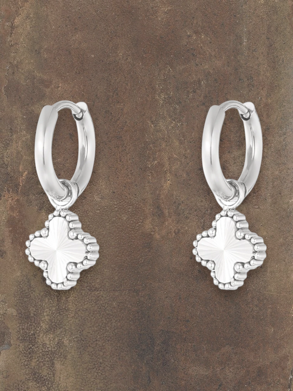 WILDSIDE silver hoop earrings with a textured clover charm. Elegant and classic design.