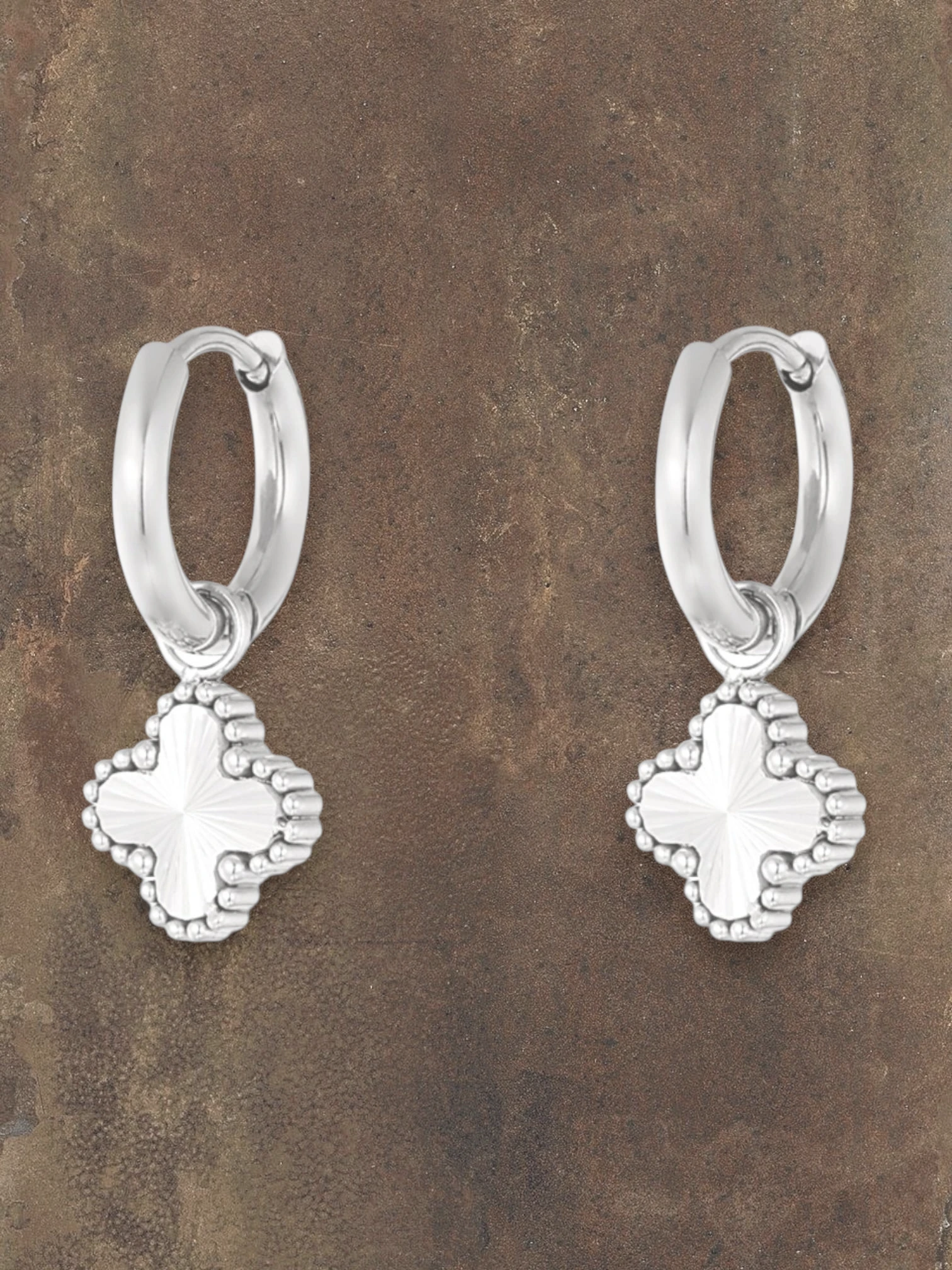WILDSIDE silver hoop earrings with a textured clover charm. Elegant and classic design.