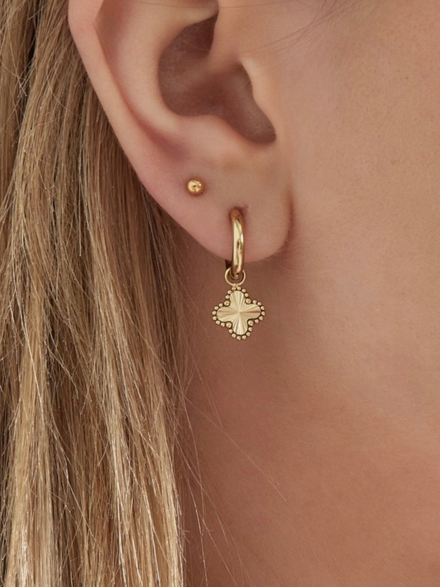 WILDSIDE gold clover charm hoop earrings with textured detail and a small gold stud earring.