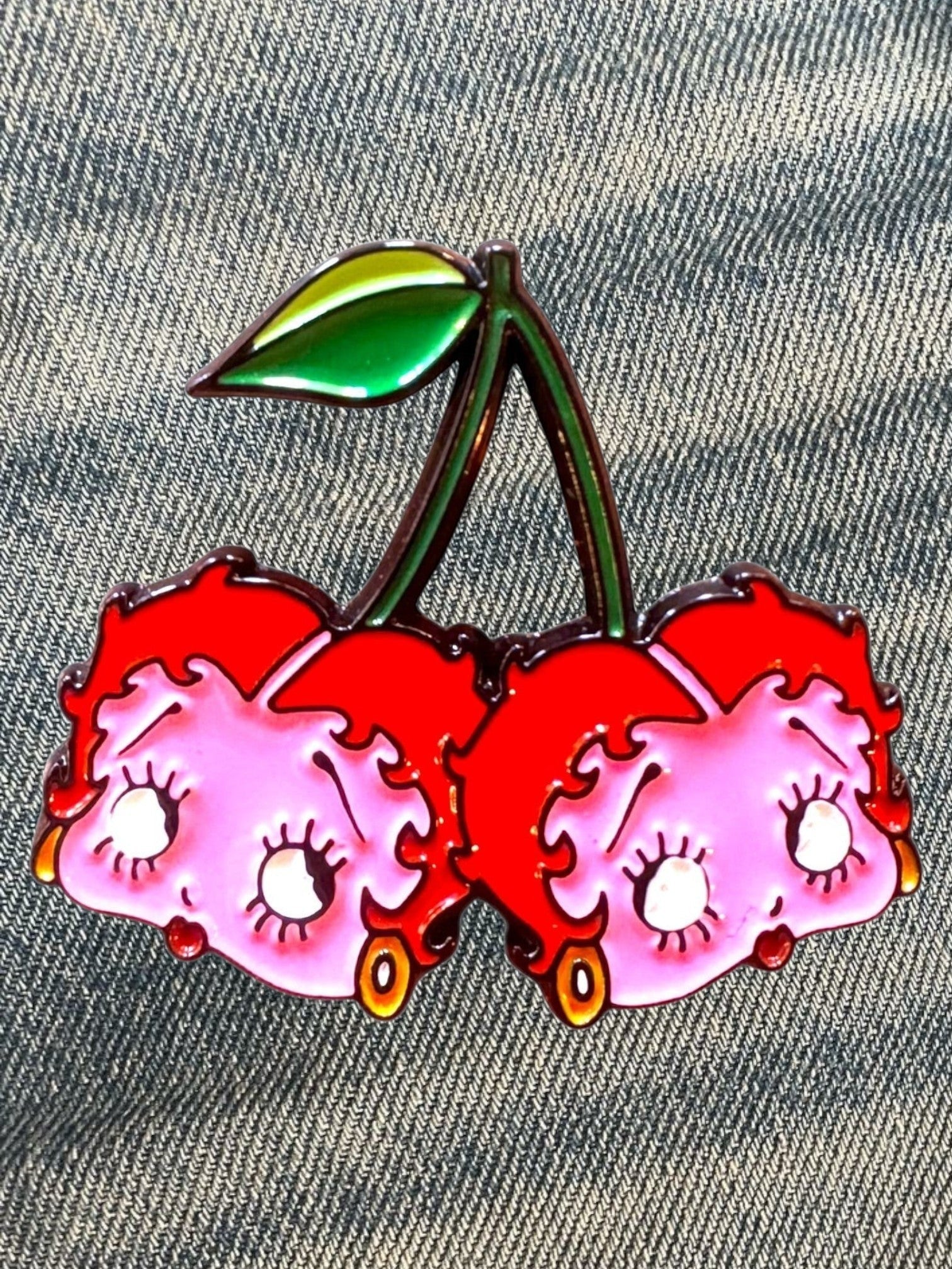 WILDSIDE Betty Boop cherry pin with pink faces, red tops, and green leaves. Enamel accessory.