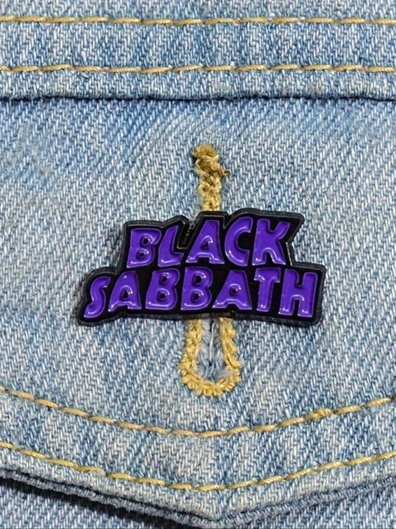 WILDSIDE Black Sabbath logo enamel pin in purple and black on denim.