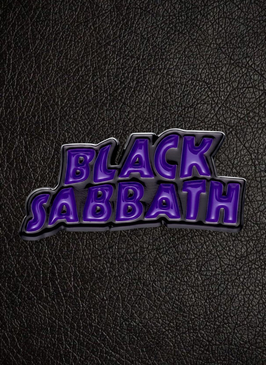 WILDSIDE Black Sabbath purple and black enamel pin with metallic silver border on a rusty metal background.