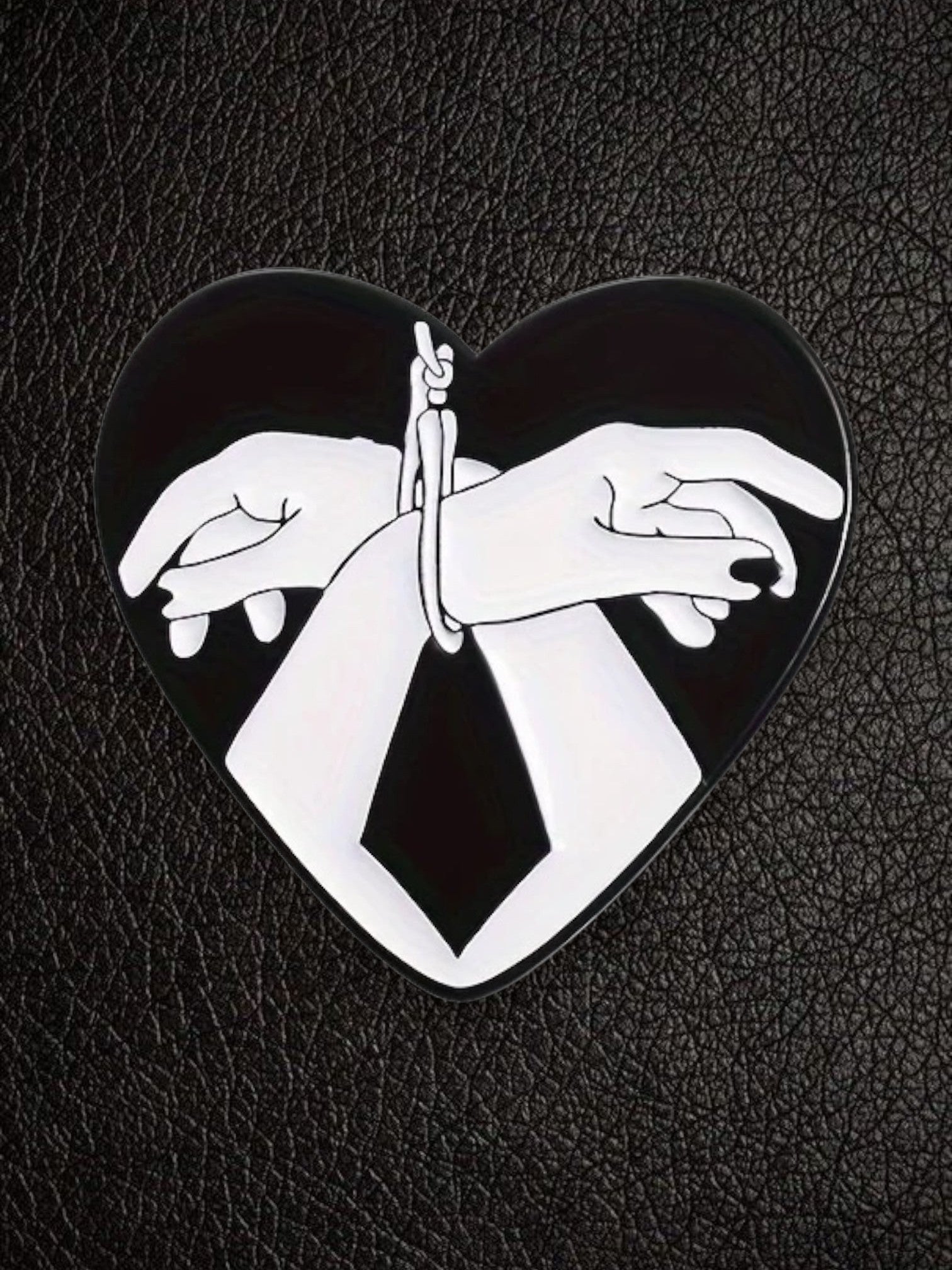 WILDSIDE black and white heart hands bondage pin with glossy enamel finish.