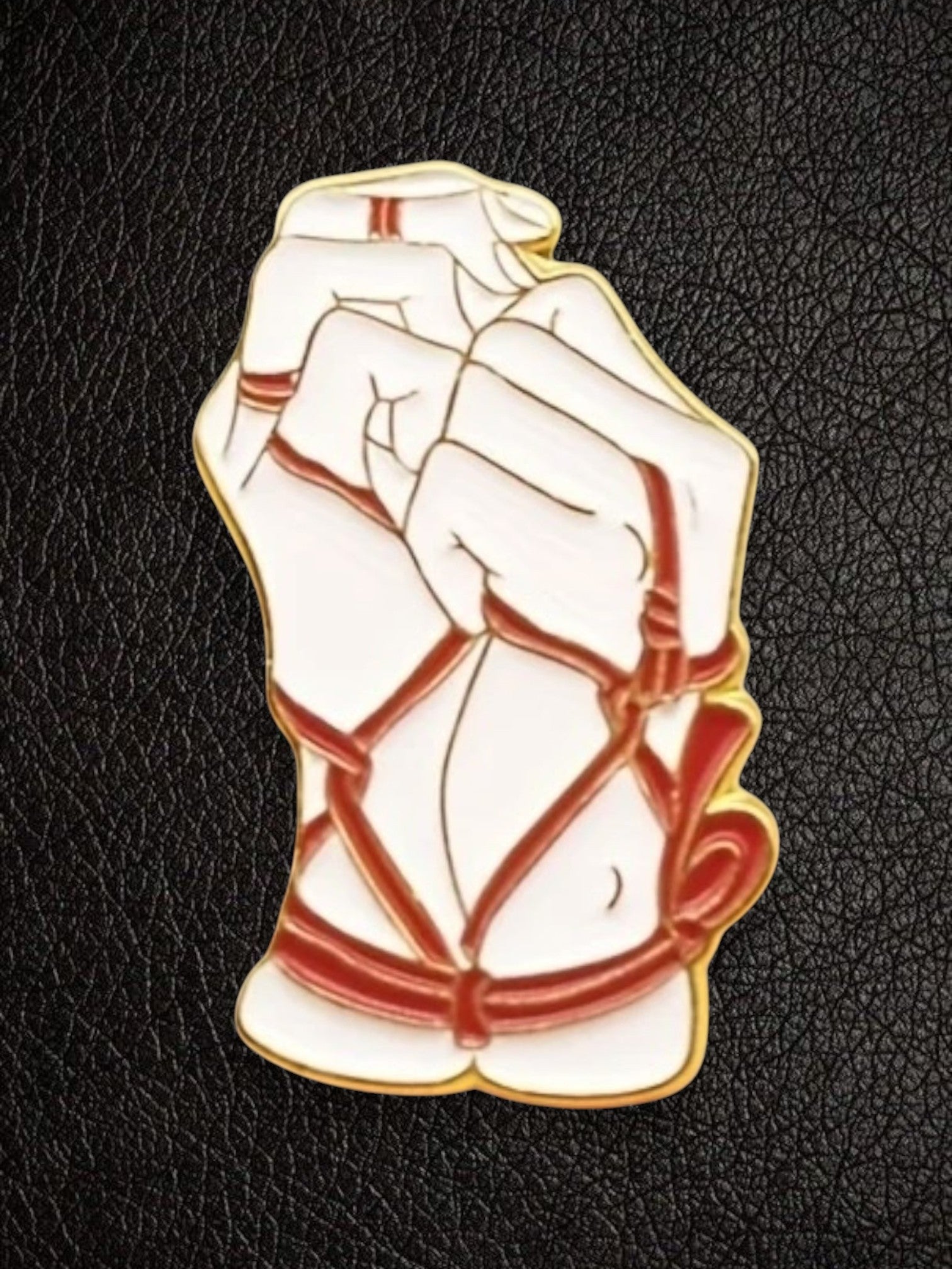 WILDSIDE bondage pin featuring white hands tied with red rope, gold trim.