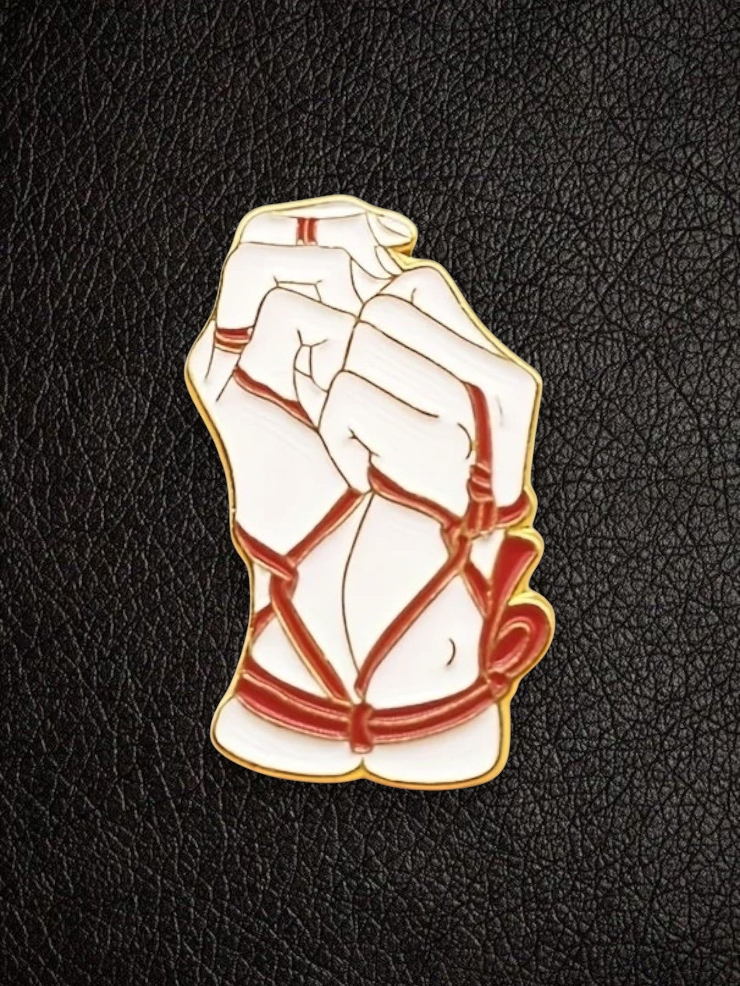 WILDSIDE bondage pin featuring white hands bound with red rope detail, gold trim.