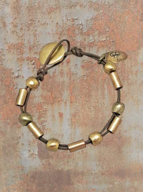 WILDSIDE brown leather bracelet with gold-tone beads and a knot closure. Features a leaf-shaped charm and a small oval brand tag.