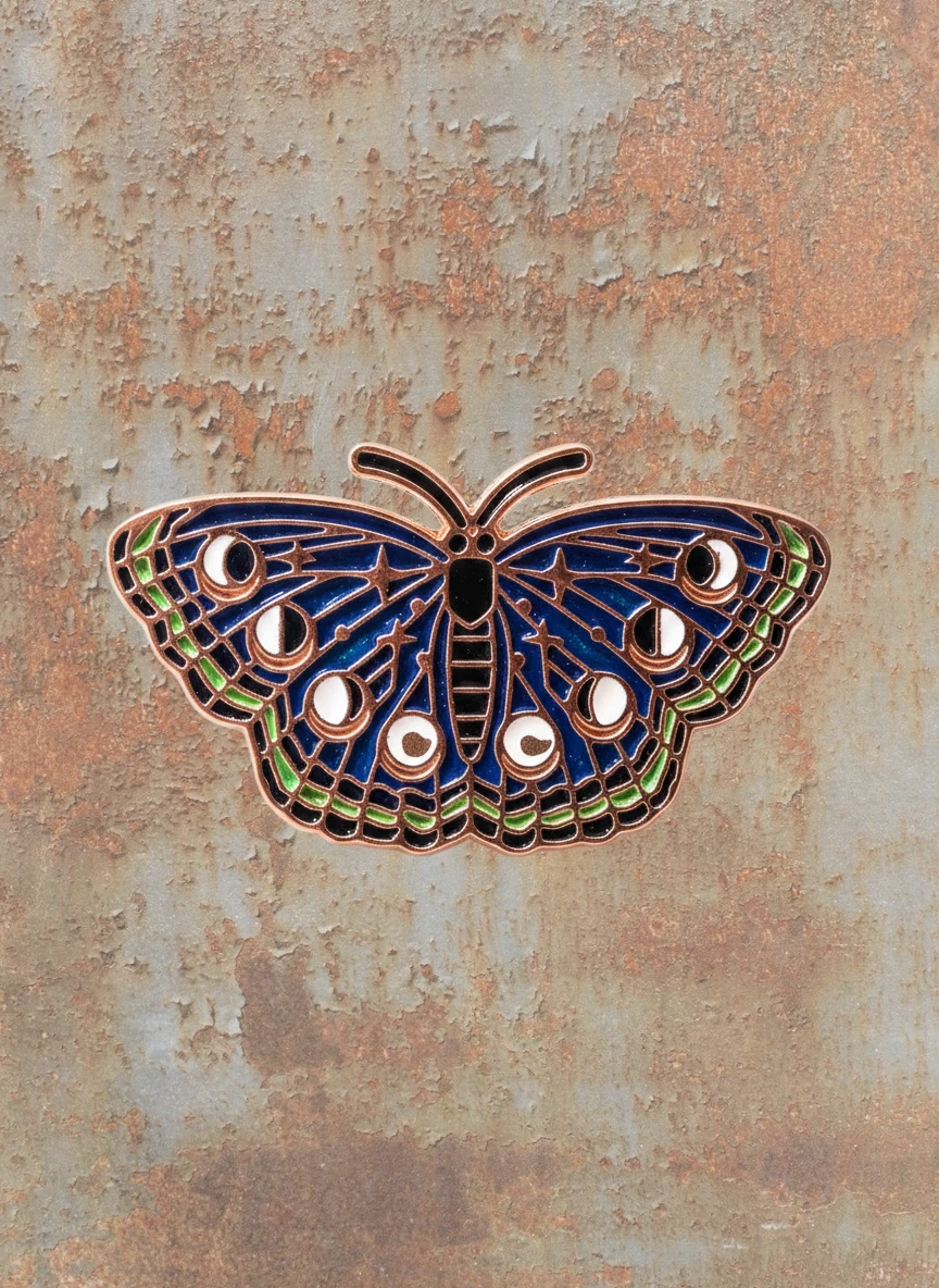 WILDSIDE dark blue butterfly enamel pin with moon phases and stars design.