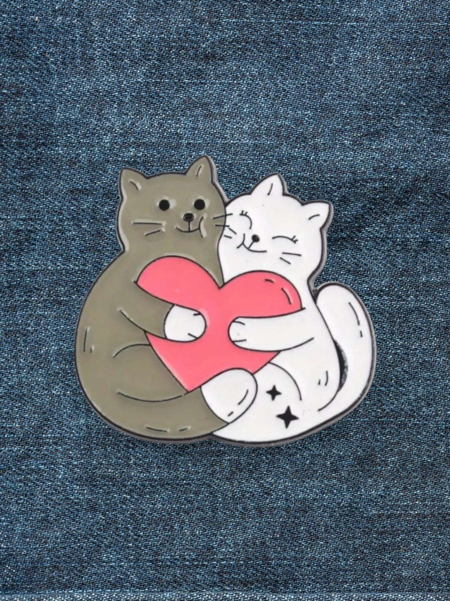 WILDSIDE enamel pin of two cats, one grey and one white, hugging a pink heart.