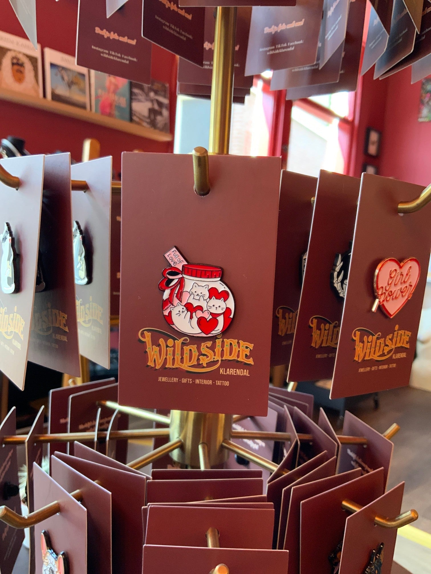 WILDSIDE enamel pin featuring a jar filled with white cats and red hearts, with a red ribbon and bow.