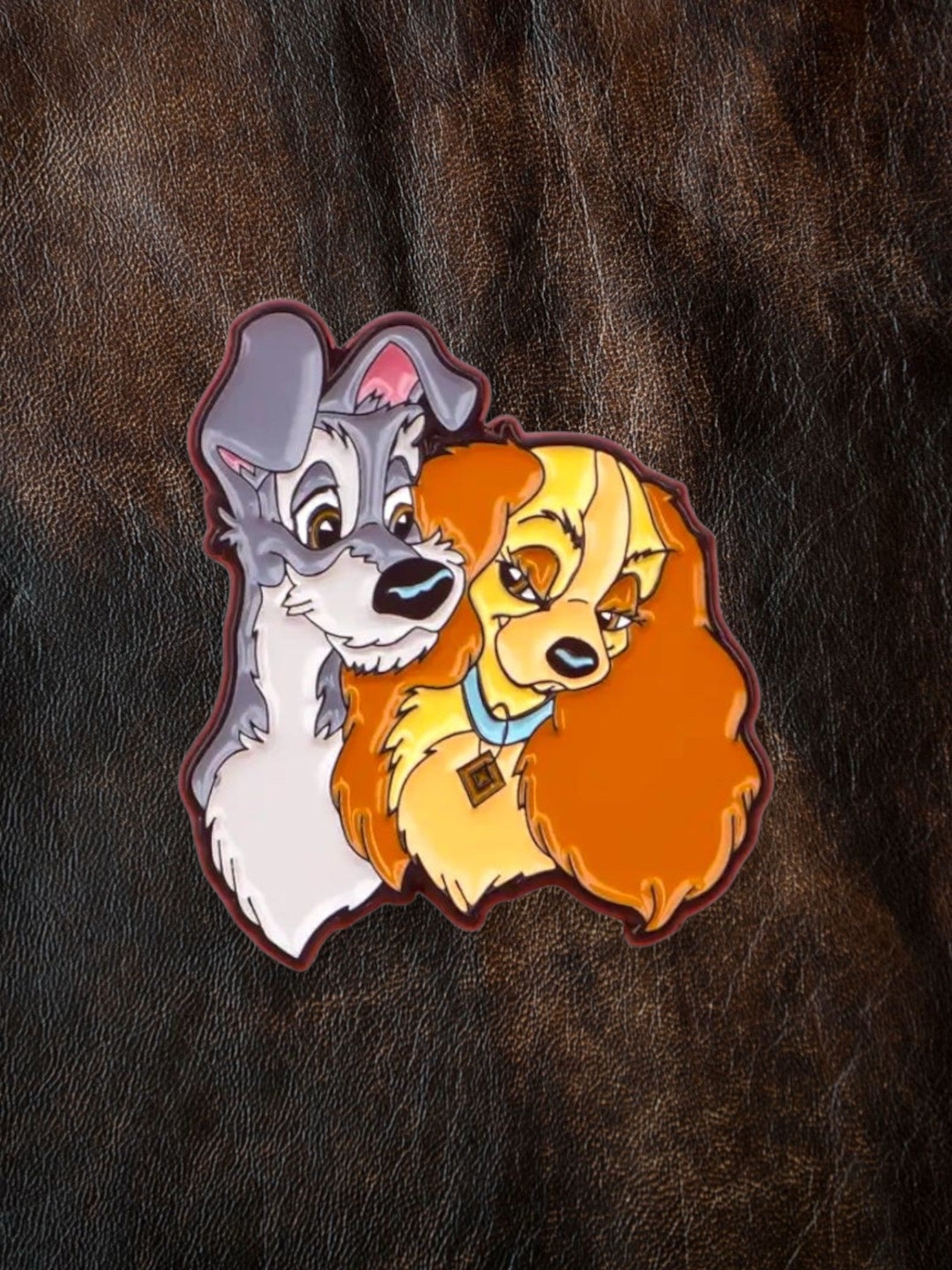 WILDSIDE Disney Lady and the Tramp enamel pin featuring the two dogs embracing. Lady has orange fur and a blue collar with a diamond tag.