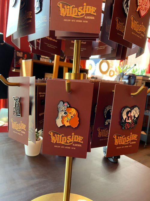 WILDSIDE enamel pin featuring Disney dogs Lady and the Tramp embracing. Metal pin with colourful design.