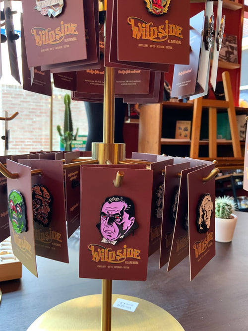 WILDSIDE enamel pin featuring a graphic portrait of Dracula in pink, black, and red with a white collar.