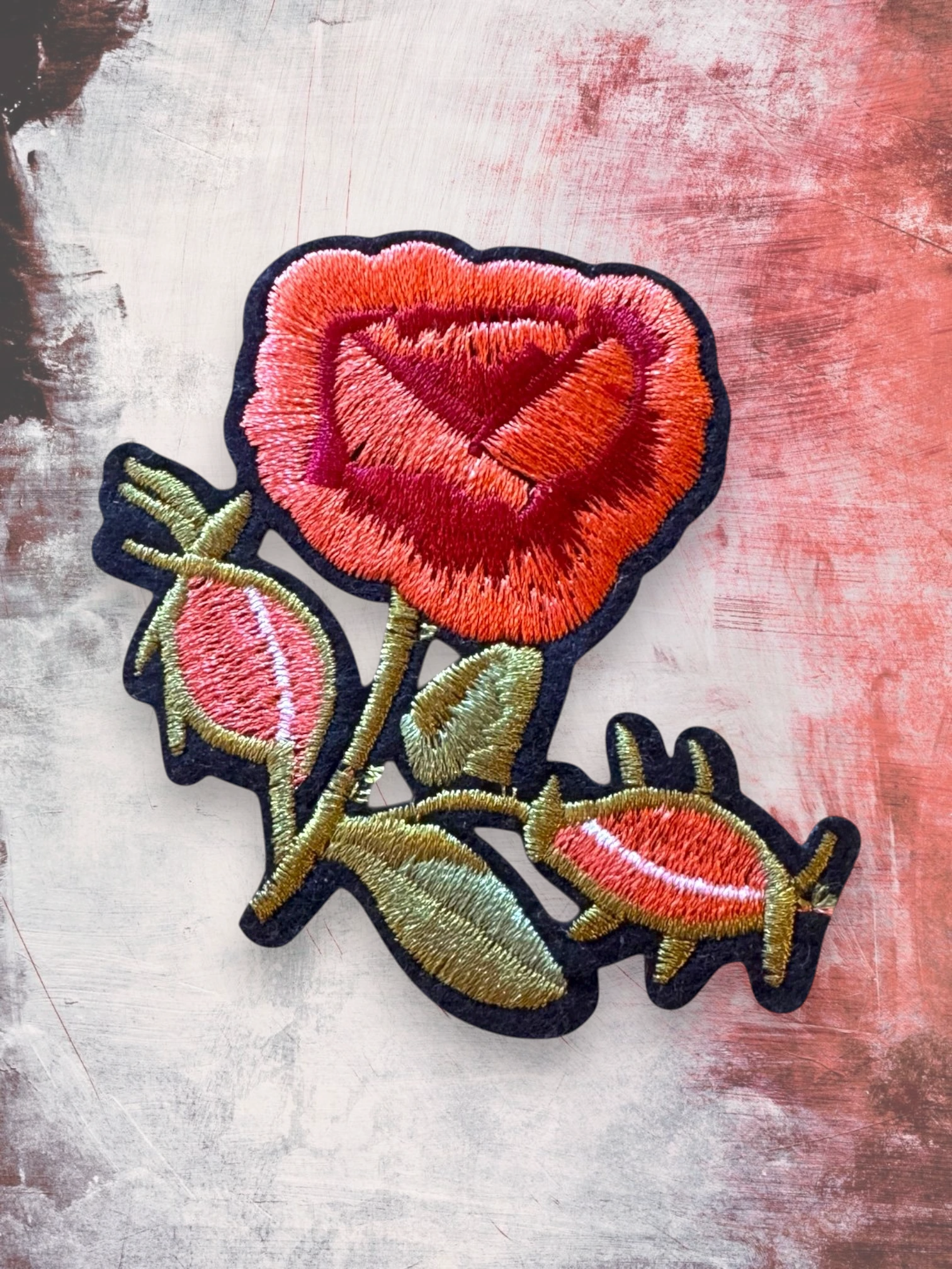 WILDSIDE embroidered patch of a red and orange rose with green leaves and buds. Features a black border.