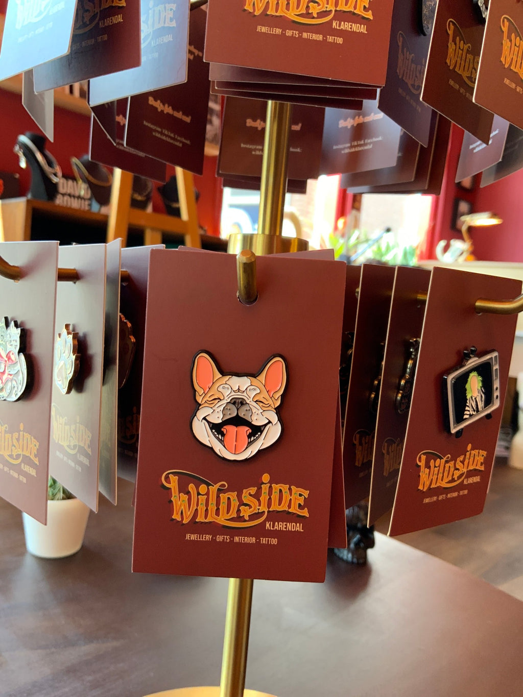 WILDSIDE enamel pin featuring a happy French Bulldog with its tongue out, attached to a burgundy display card.
