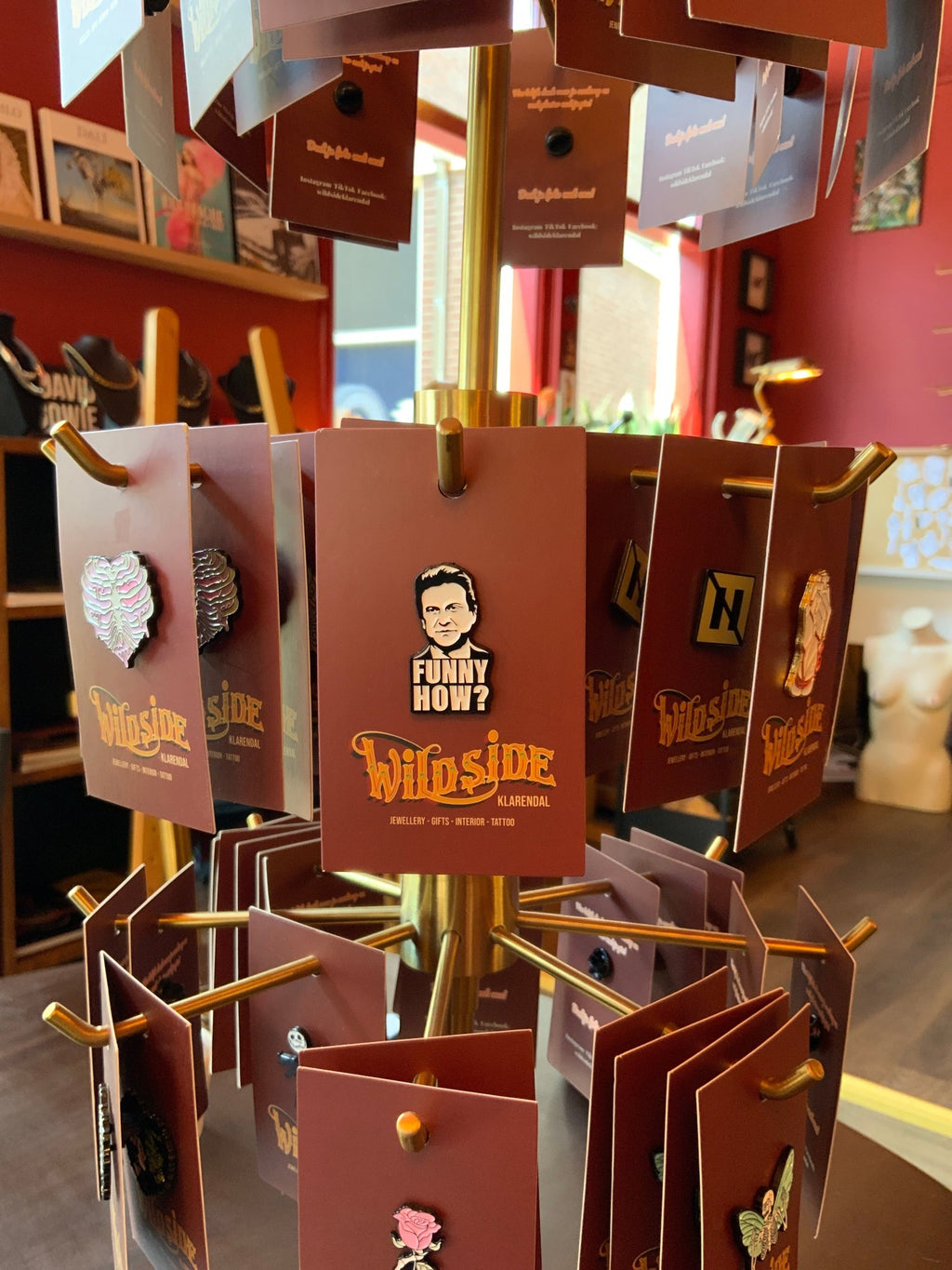 WILDSIDE enamel pin featuring a black and white portrait with 'FUNNY HOW?' text above, mounted on a brown card.