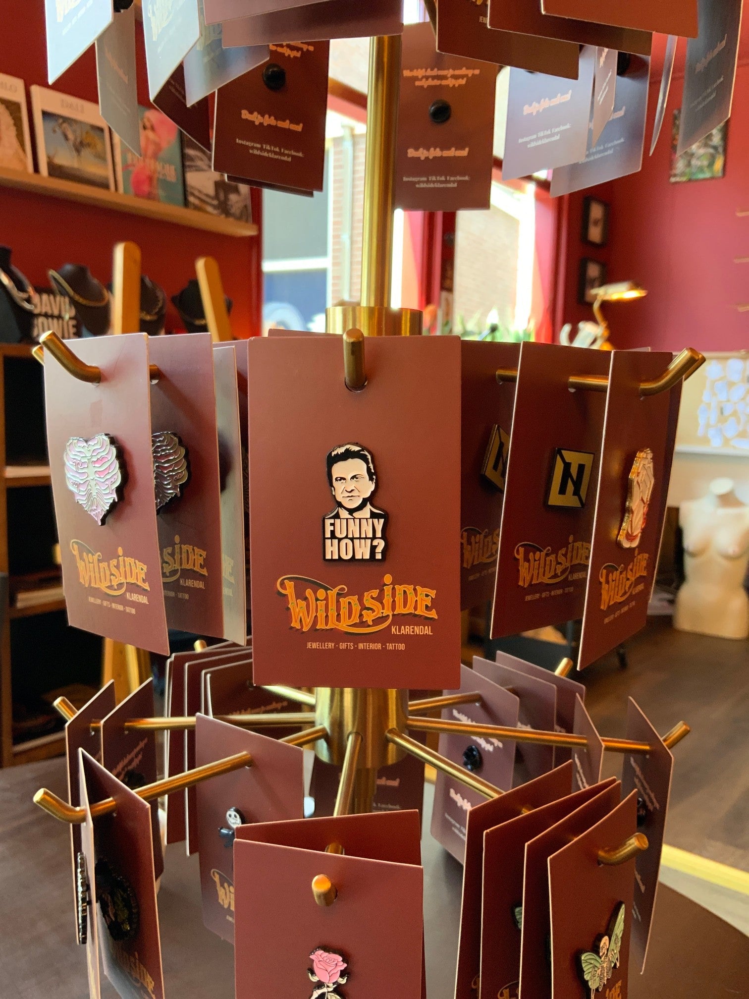 WILDSIDE enamel pin featuring a black and white portrait with 'FUNNY HOW?' text above, mounted on a brown card.