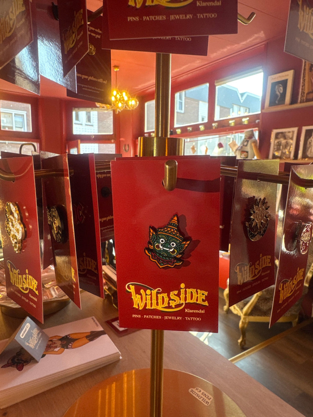 WILDSIDE enamel pin featuring a green mythical creature with a large mouth and white eyes, on a red backing card.
