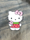 WILDSIDE Hello Kitty strawberry pin with pink bow and flower, on denim.