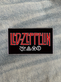 WILDSIDE Led Zeppelin rectangular pin with red lettering and four symbols on a black background.