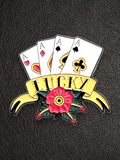 WILDSIDE Lucky Aces poker pin with four Aces, a banner saying LUCKY, and a red rose with green leaves. Tattoo-inspired enamel pin.