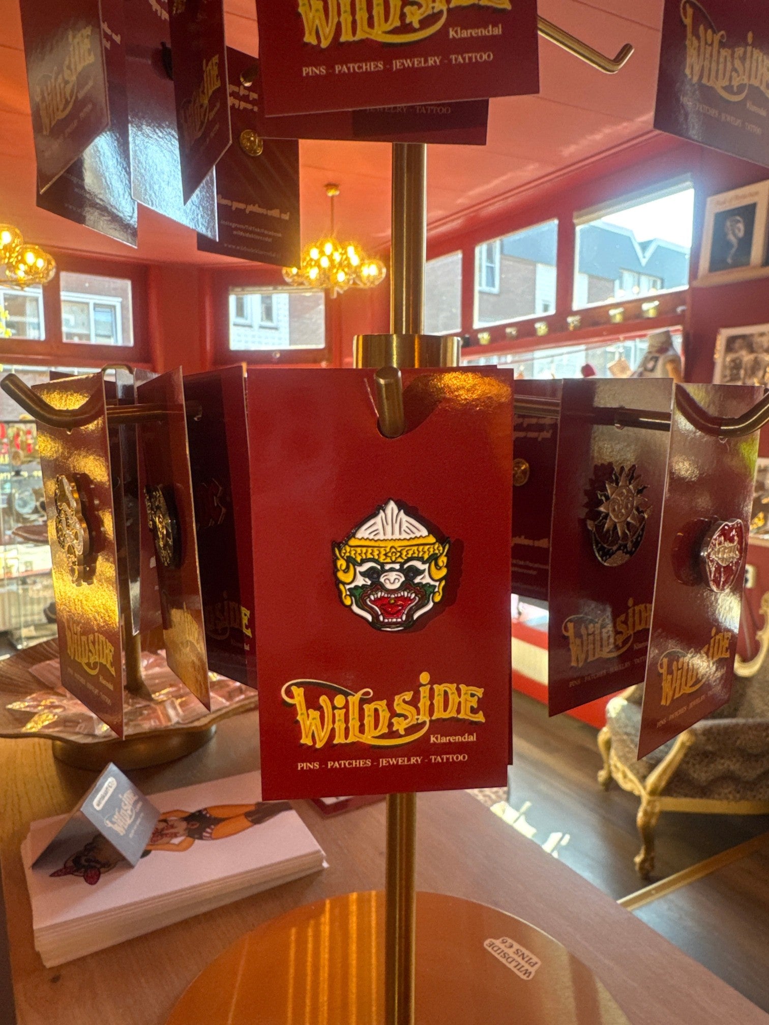 WILDSIDE enamel pin featuring a fierce monkey face with white, green, and red details, mounted on a red card.