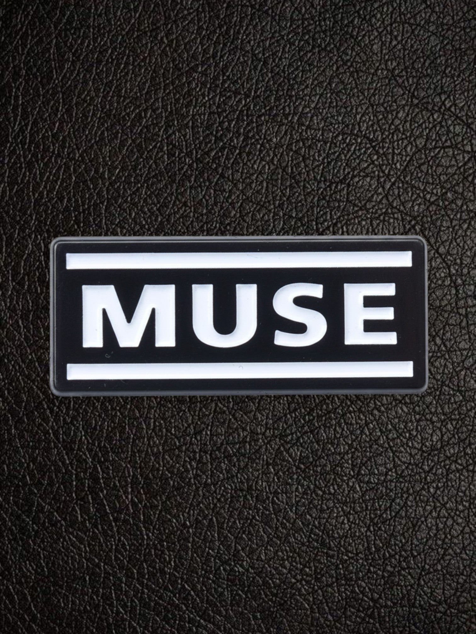 WILDSIDE black rectangular pin with white text spelling MUSE, featuring two white horizontal lines above and below the text.