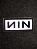 WILDSIDE Nine Inch Nails NIN logo pin with black lettering on a white background, rectangular shape.