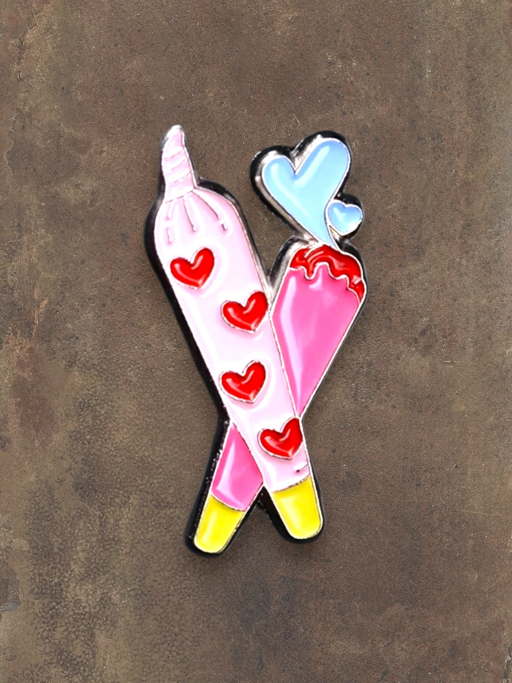 WILDSIDE pink enamel pin with red hearts and blue hearts, shaped like crossed joints.