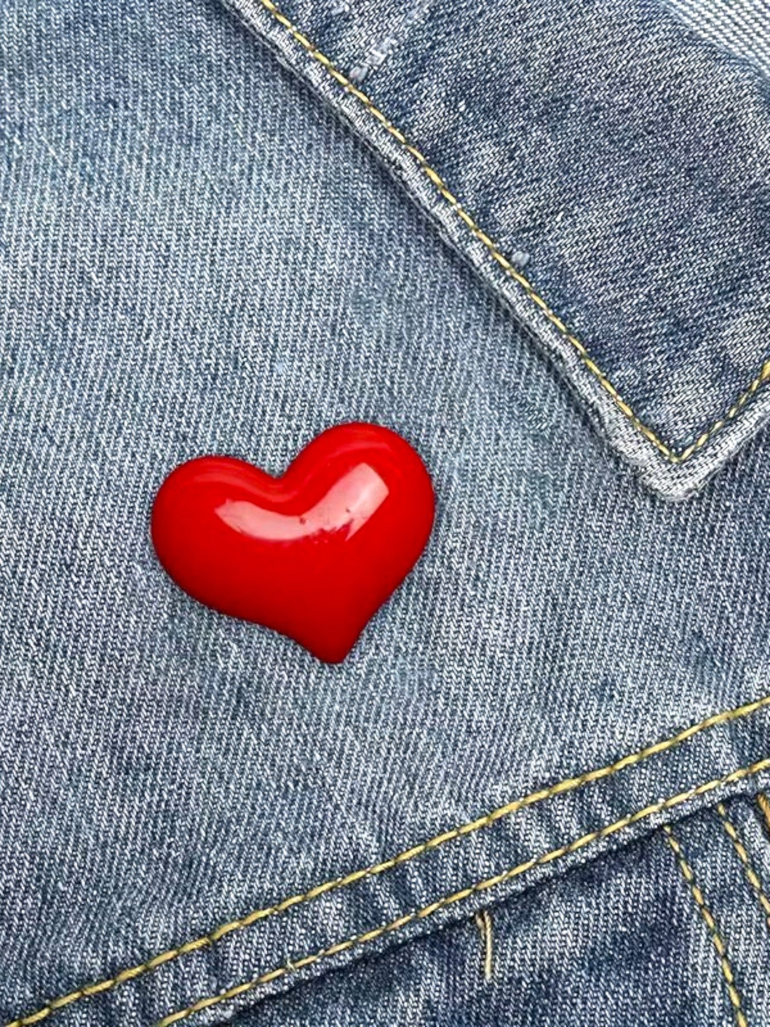 WILDSIDE red heart-shaped enamel pin on denim jacket.