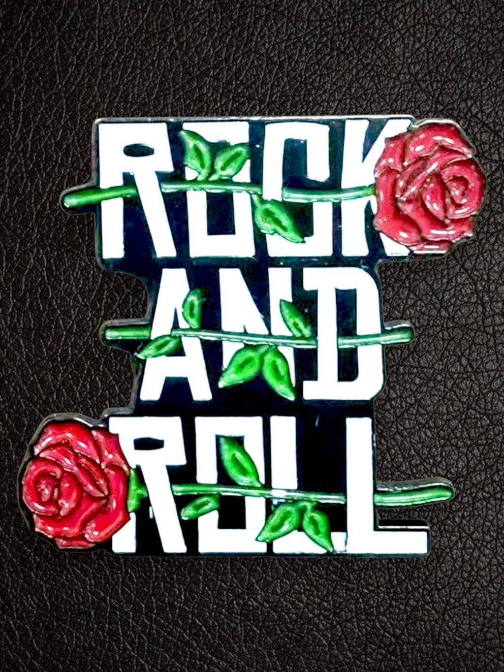 WILDSIDE rock and roll enamel pin with red roses and green leaves on a black background.