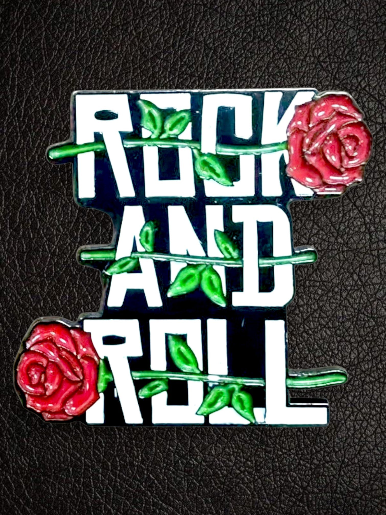 WILDSIDE rock and roll enamel pin with red roses and green leaves on a black background.