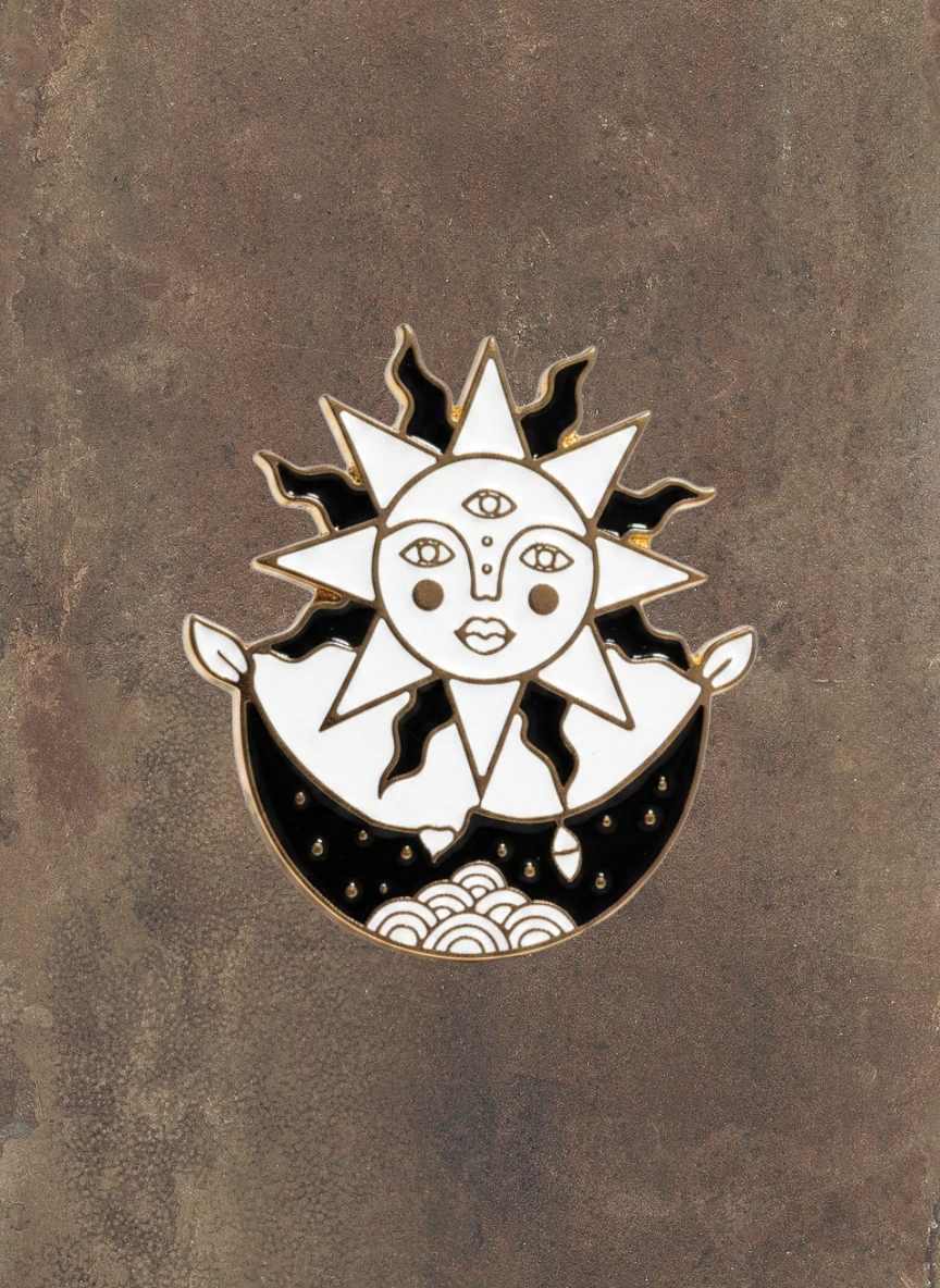 WILDSIDE enamel pin featuring a celestial sun with a face and third eye, set against a crescent moon with cloud details.