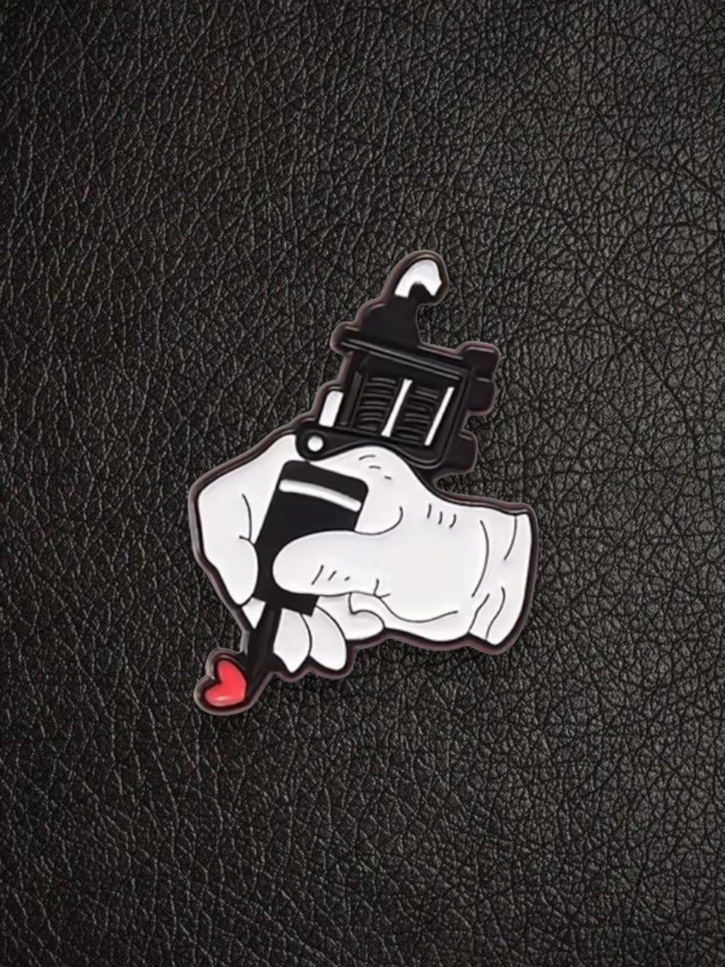 WILDSIDE tattoo gun pin with a hand holding it, creating a red heart.