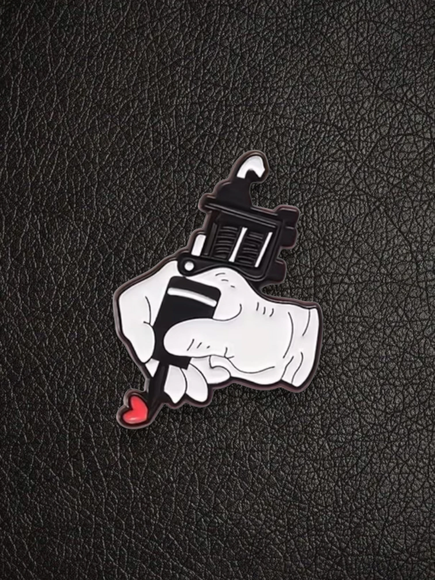 WILDSIDE tattoo gun pin with a hand holding it, creating a red heart.