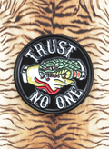 WILDSIDE Trust No One pin featuring a hand crushing a snake, with red and yellow accents.